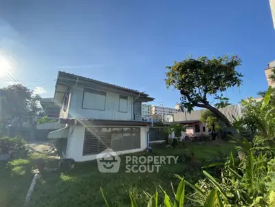 Charming two-story house with lush garden and clear blue sky backdrop