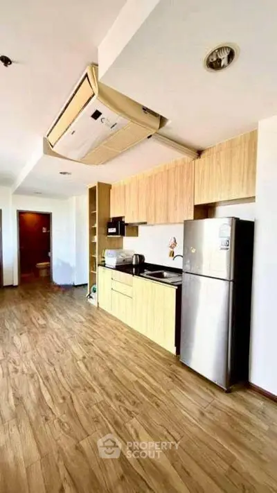 Modern kitchen with sleek appliances and wooden cabinetry in a stylish apartment.