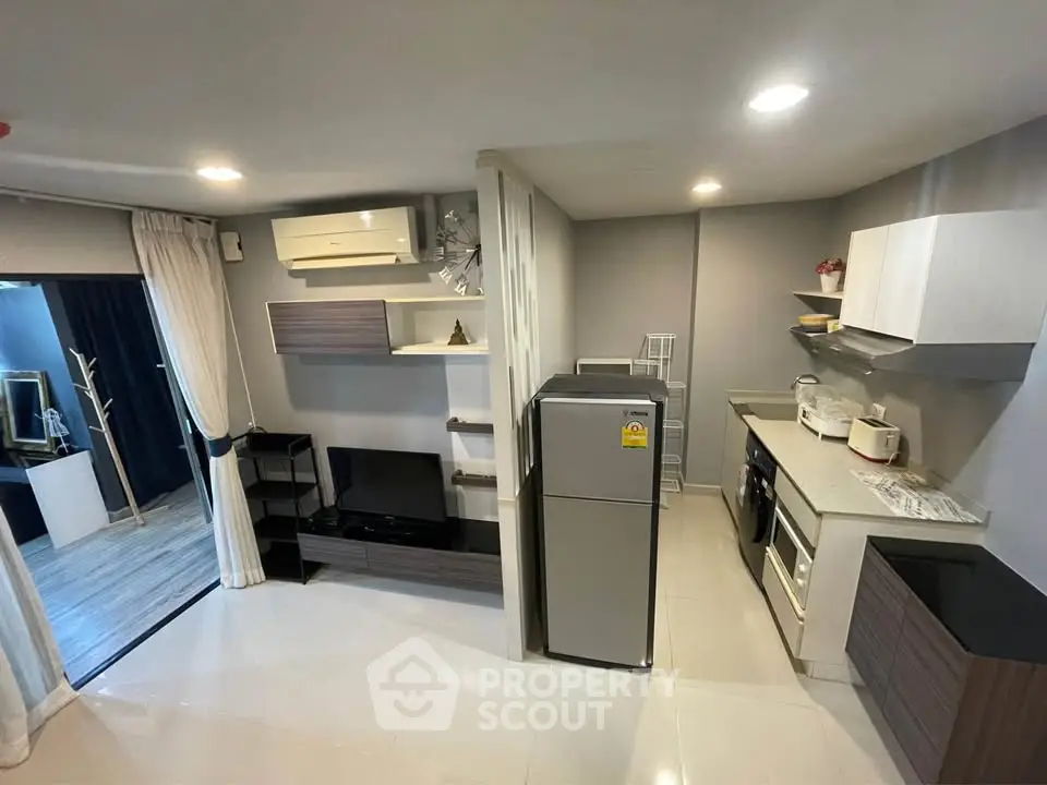 Modern open-layout living room and kitchen with sleek appliances and stylish decor.