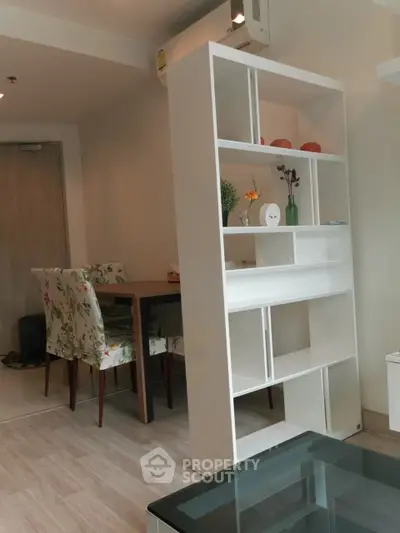 Modern living room with stylish shelving and dining area in cozy apartment.