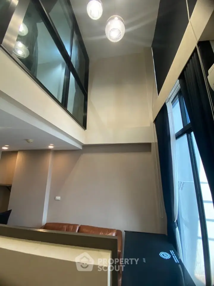 Modern loft-style living room with high ceilings and large windows