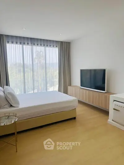 Modern bedroom with large window and minimalist decor, featuring a sleek TV and stylish furniture.