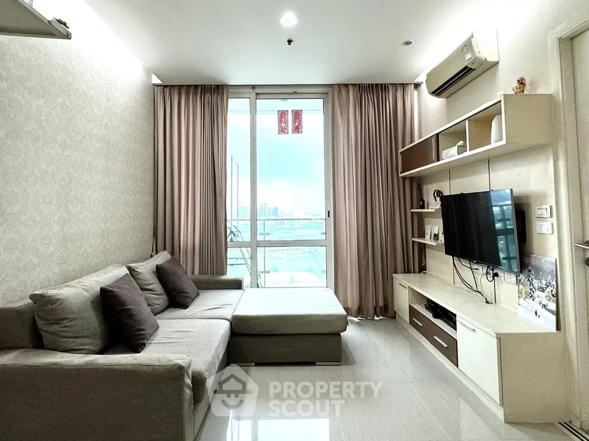 Modern living room with large sofa and city view balcony, perfect for relaxation.