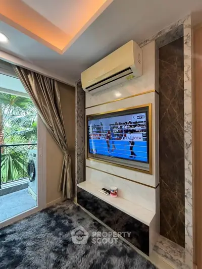 Luxurious living room with modern TV setup and balcony view, featuring elegant decor and air conditioning.