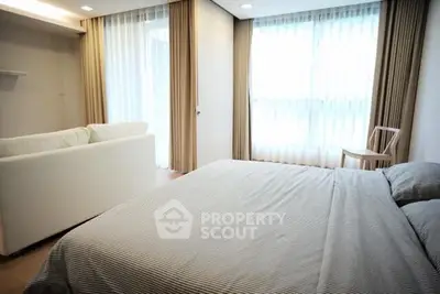 Spacious bedroom with large windows and cozy seating area