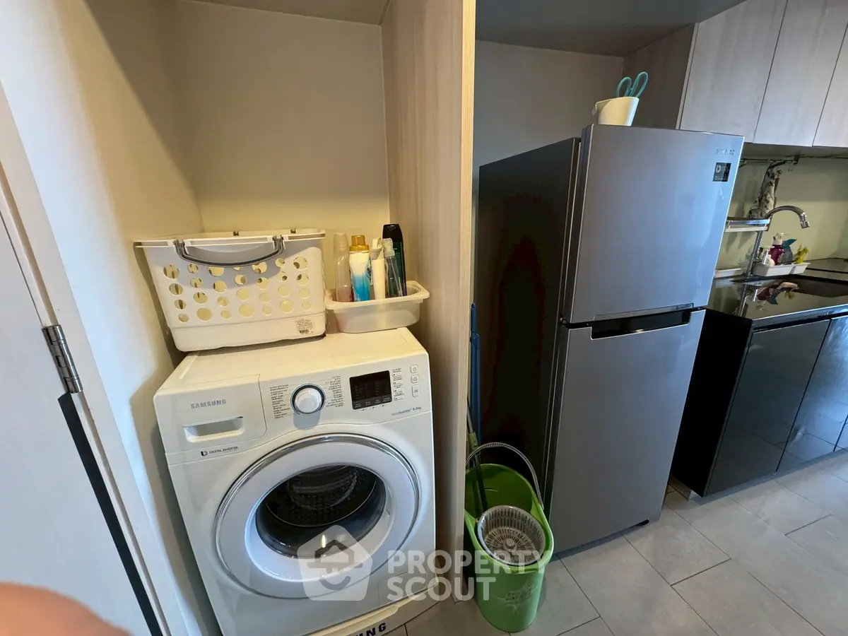 Modern kitchen with washing machine and stainless steel fridge in compact layout.
