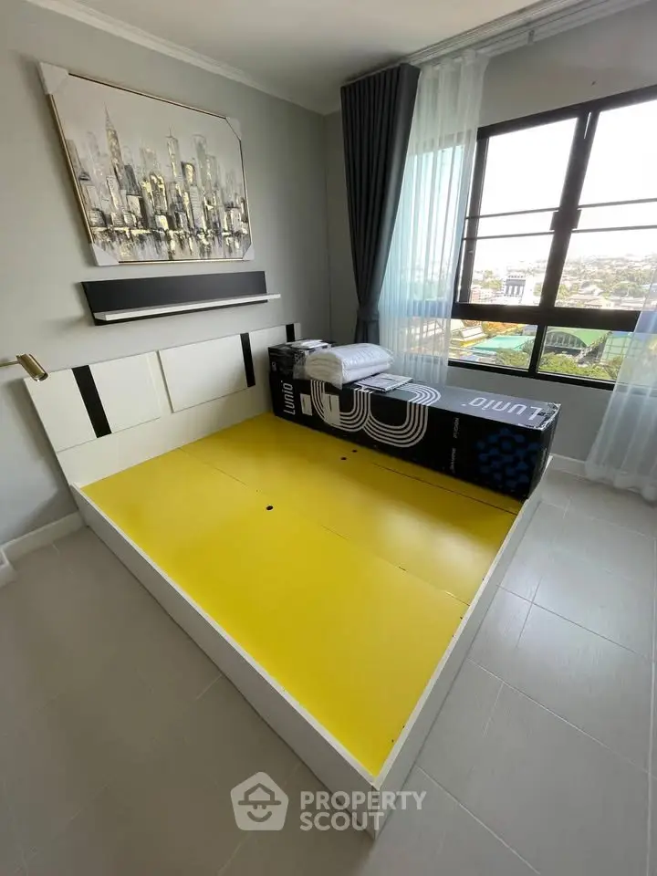 Modern bedroom with large window and city view, featuring stylish decor and natural light.