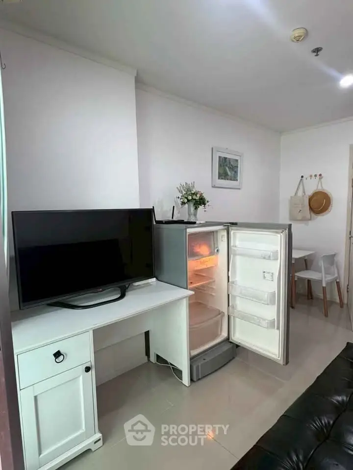Modern living room with TV, fridge, and dining area in a cozy apartment.