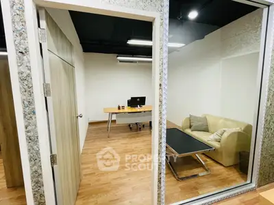 Modern office space with glass walls, wooden flooring, and stylish furniture for a professional environment.