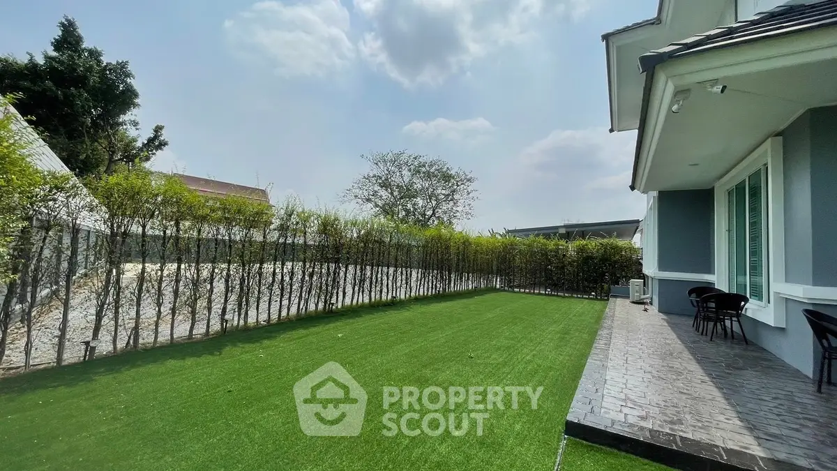Spacious backyard with lush green lawn and modern patio, perfect for outdoor relaxation and entertainment.