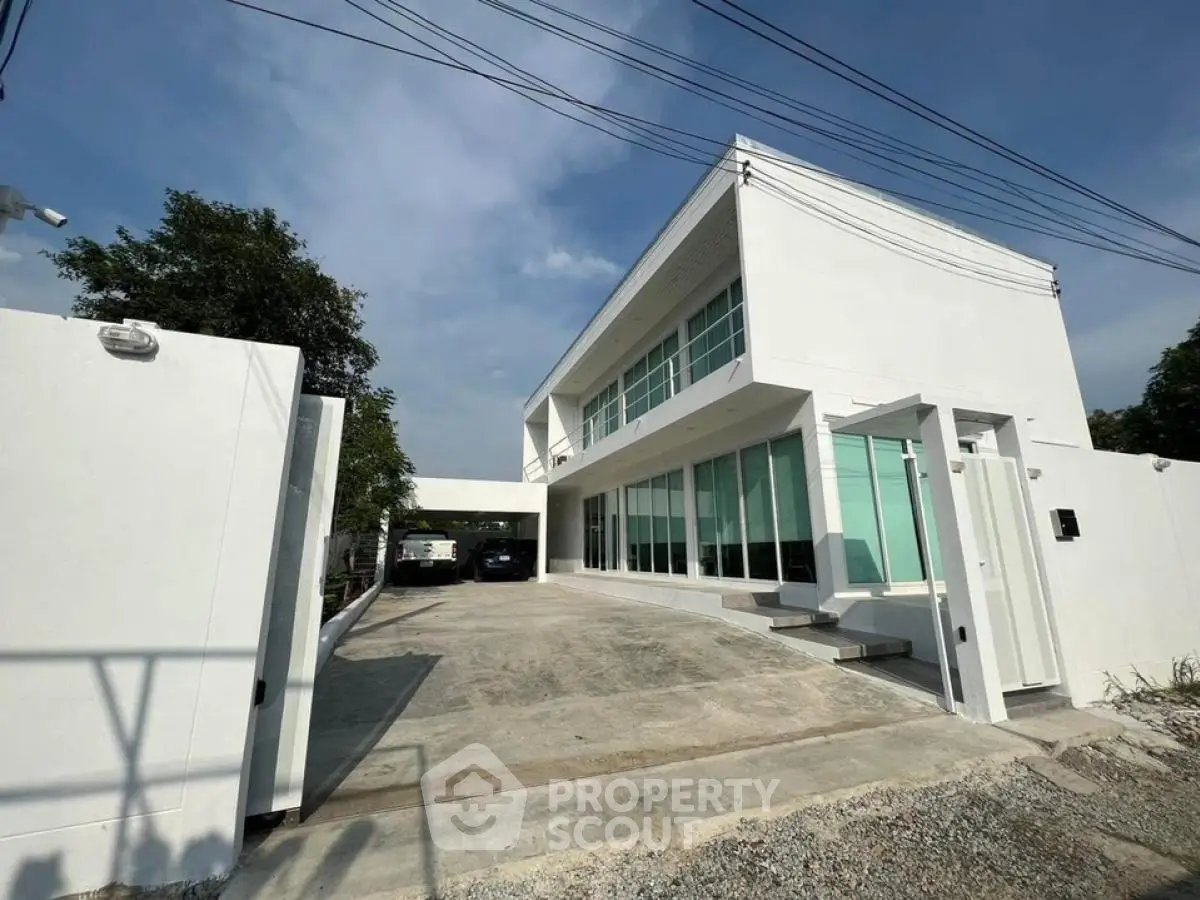 Modern white two-story house with large windows and spacious driveway