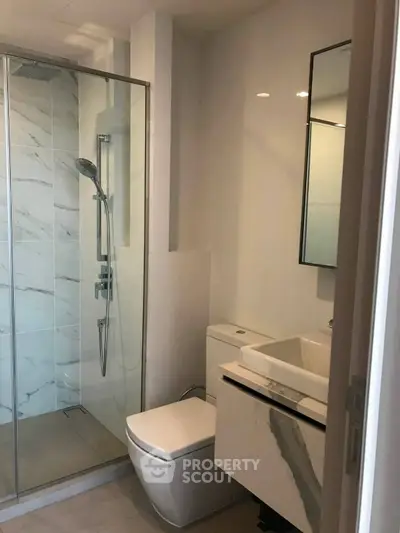 Modern bathroom with glass shower and sleek fixtures in a contemporary apartment.