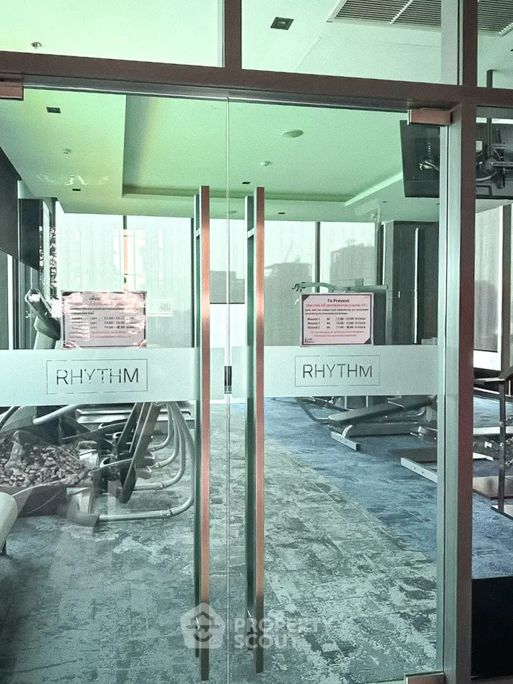 Modern gym with glass doors and fitness equipment in a luxury residential building.