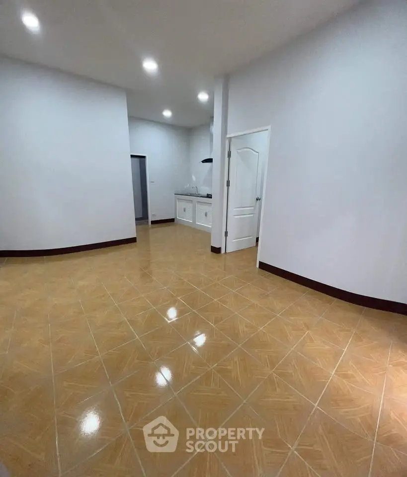 Spacious open-plan living area with modern kitchen and glossy tiled flooring.