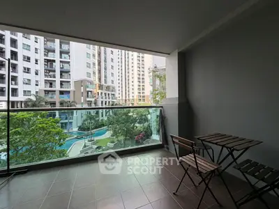 Spacious balcony with city view overlooking modern apartment complex and pool.