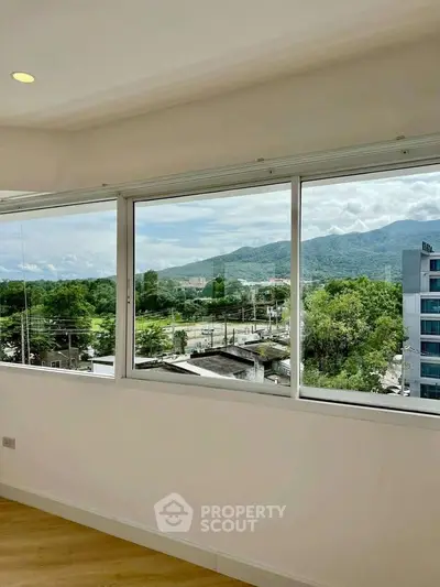 Spacious room with large windows offering stunning mountain views, perfect for a serene living experience.