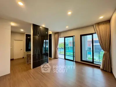 Spacious modern living room with large windows and elegant wooden flooring.