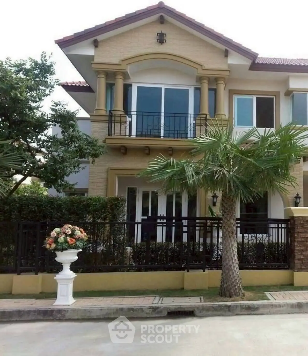 Elegant two-story house with balcony and lush garden, perfect for family living.