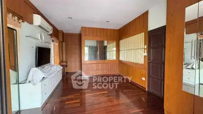 Spacious wooden interior room with large mirror and TV setup