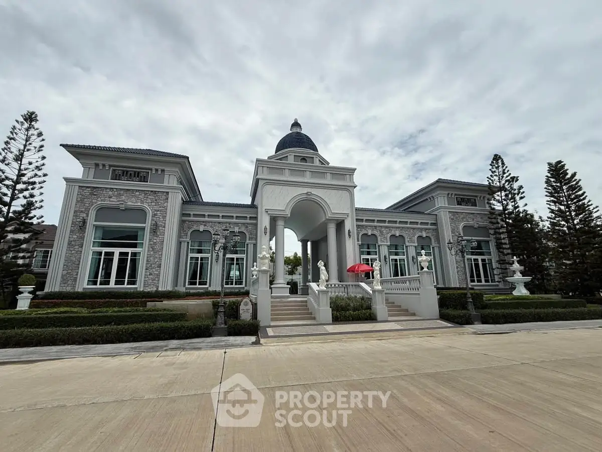 Elegant mansion with grand entrance and classic architecture, surrounded by lush greenery and a spacious driveway.