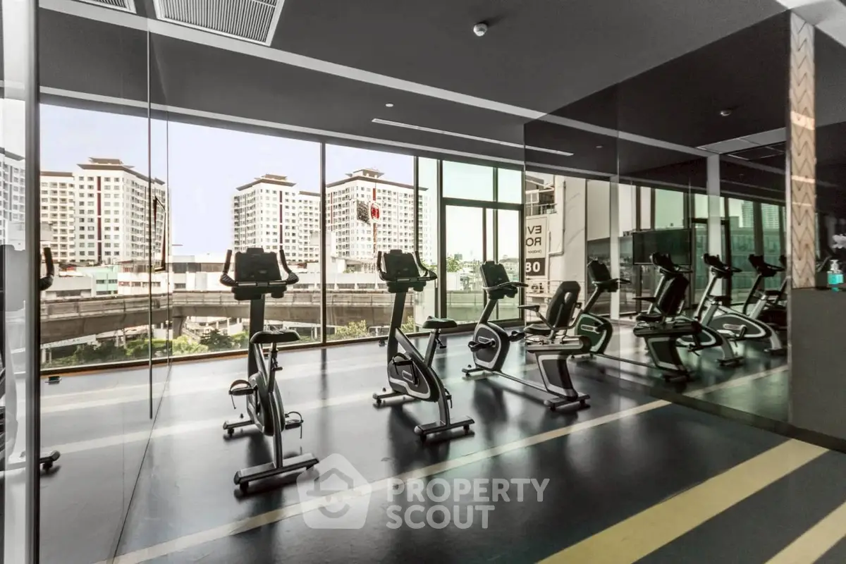 Modern gym with exercise bikes and city view in luxury apartment building.
