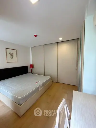 Spacious bedroom with modern design and ample natural light, featuring a large bed and sleek wooden flooring.