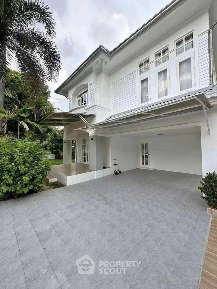 Elegant two-story white house with spacious driveway and lush greenery