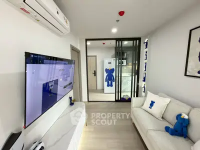 Modern living room with stylish decor and large TV, featuring a cozy sofa and air conditioning.