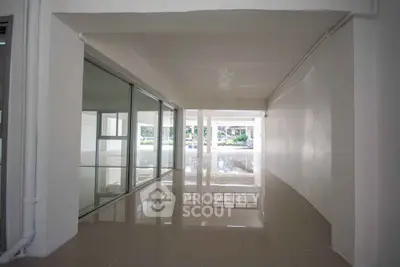 Spacious hallway with glossy tiled floors and large windows in modern building