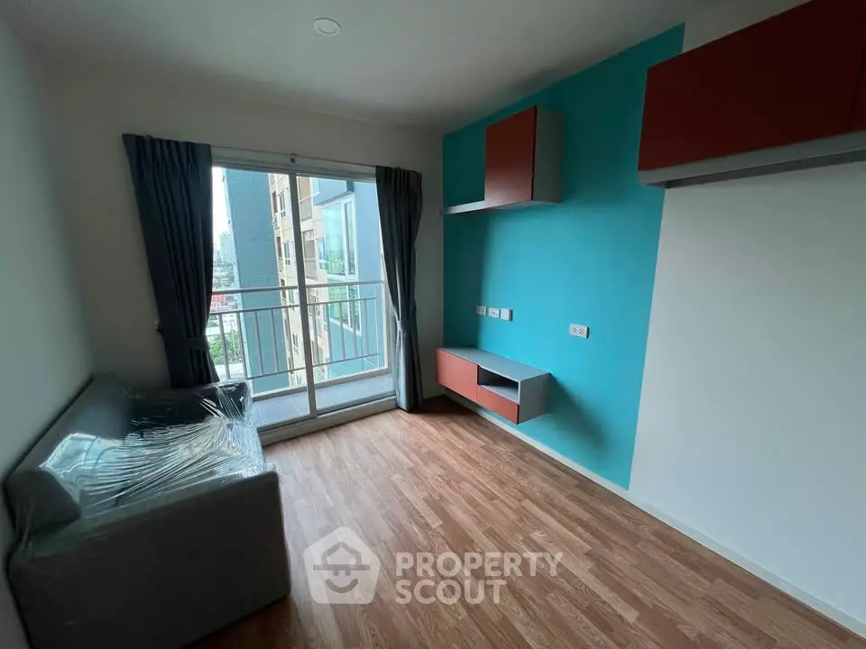 Modern living room with balcony and stylish wall storage in urban apartment.