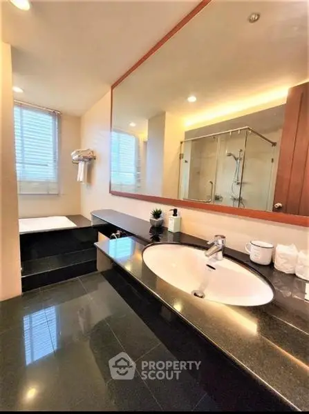 Luxurious bathroom with sleek black countertops and spacious shower area