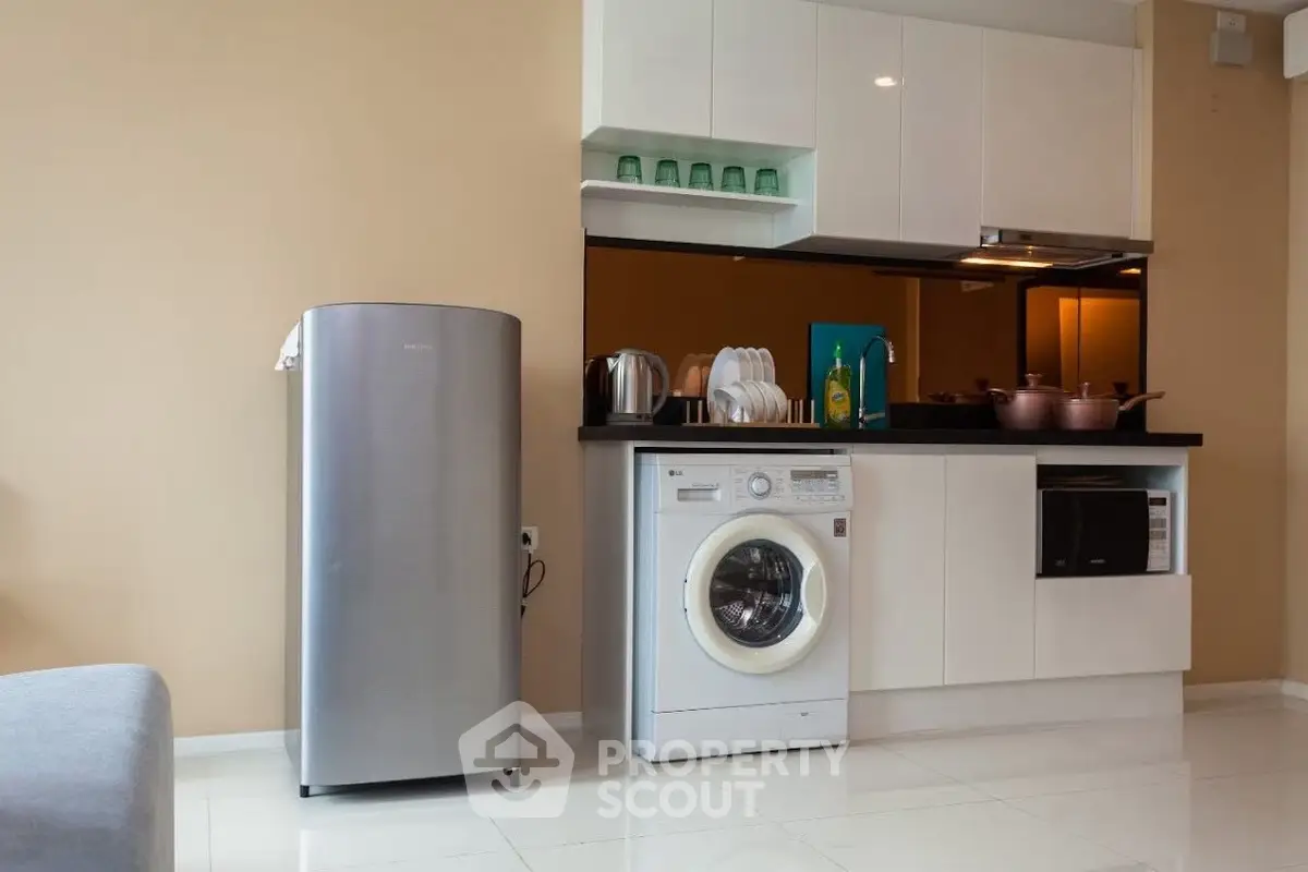 Modern kitchen with sleek appliances and washing machine in stylish apartment.