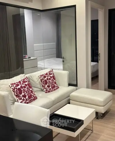 Modern living room with white sofa and red pillows, open view to bedroom, sleek design.