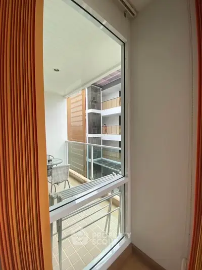 Modern apartment balcony with glass railing and outdoor seating