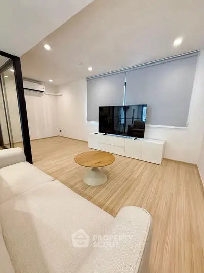Modern living room with sleek design, featuring a large TV, cozy sofa, and stylish wooden flooring.