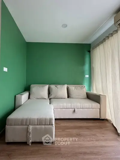 Modern living room with green accent wall and beige sectional sofa