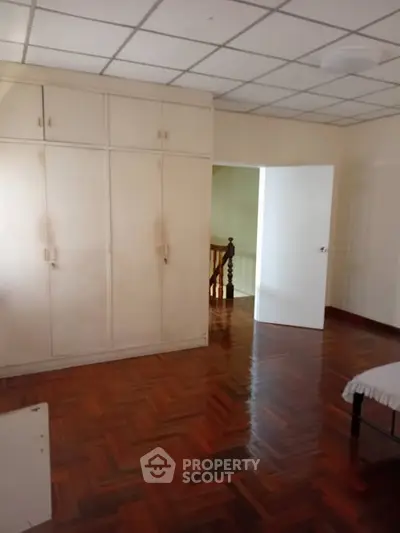 Spacious bedroom with wooden flooring and built-in wardrobe, perfect for cozy living.