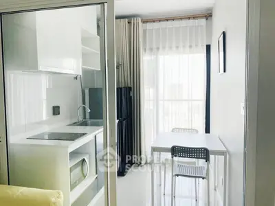 Modern kitchen with sleek white cabinetry and dining area in bright apartment