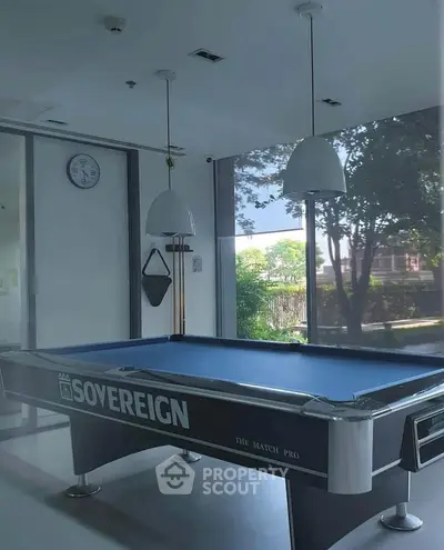 Stylish recreation room with pool table and large windows offering garden views.