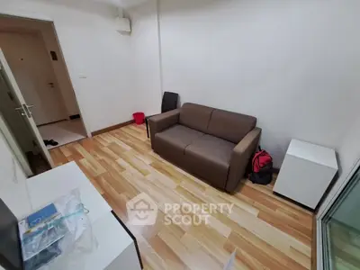 Cozy living room with modern sofa and wooden flooring in a compact apartment.