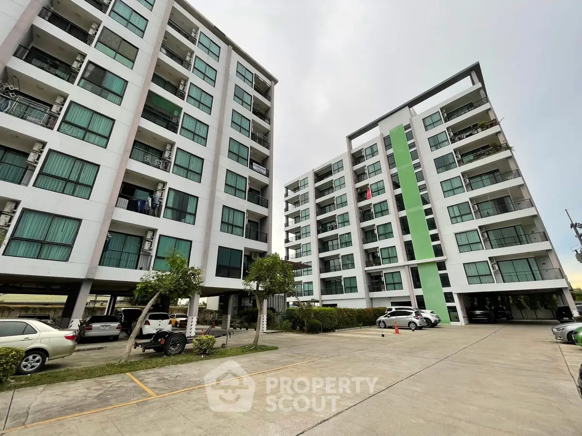 Modern apartment buildings with parking area and green accents, showcasing urban living.