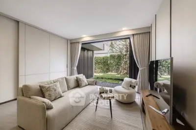 Modern living room with large sofa, TV, and garden view through sliding doors.