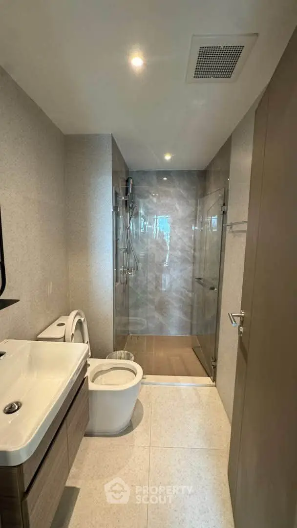 Modern bathroom with glass shower and sleek fixtures in a contemporary apartment.