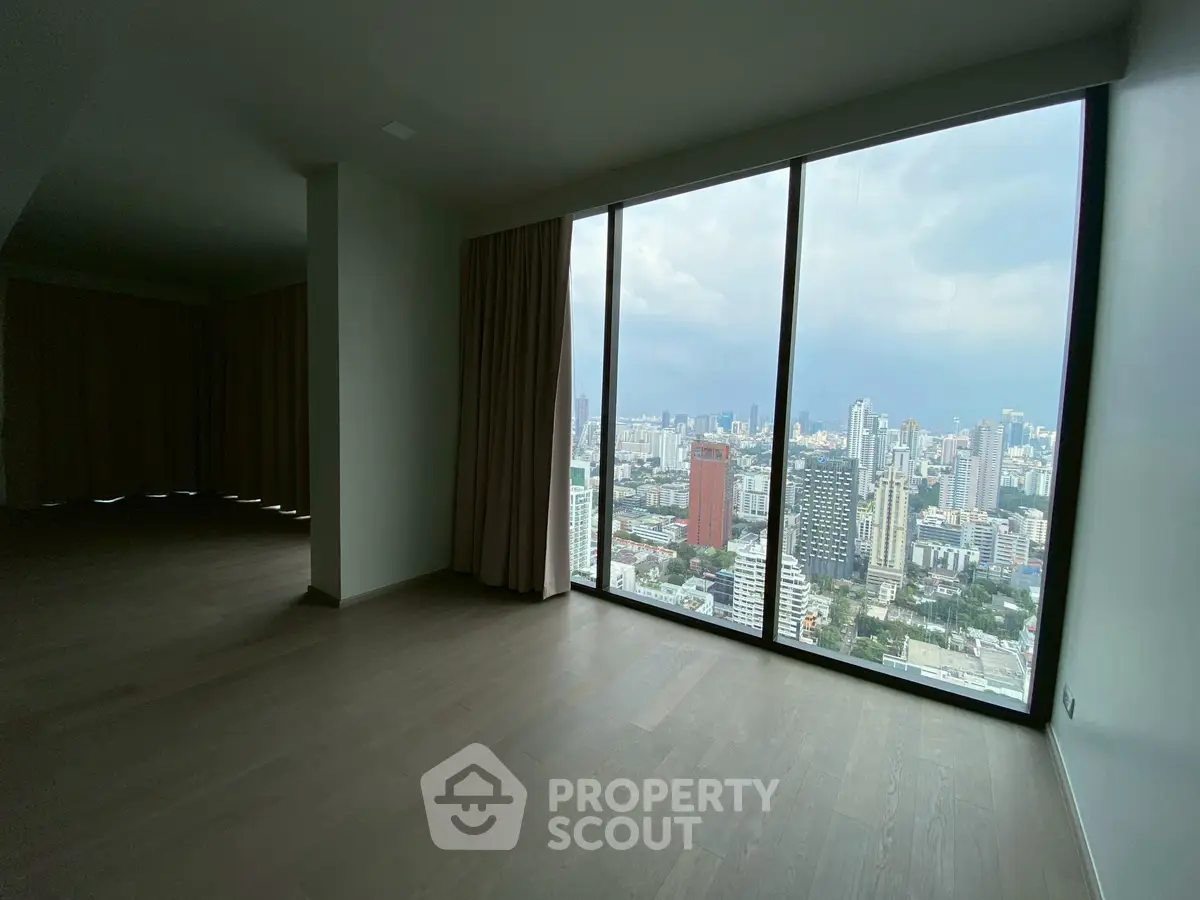 Spacious high-rise apartment with panoramic city view through floor-to-ceiling windows.