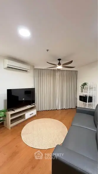 Modern living room with sleek furniture, wooden flooring, and ceiling fan, perfect for cozy gatherings.