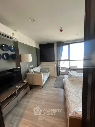 Modern studio apartment with stylish decor and large window offering natural light.