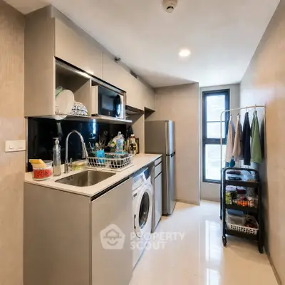 Modern kitchen with sleek cabinetry, washing machine, and stainless steel appliances in a compact layout.