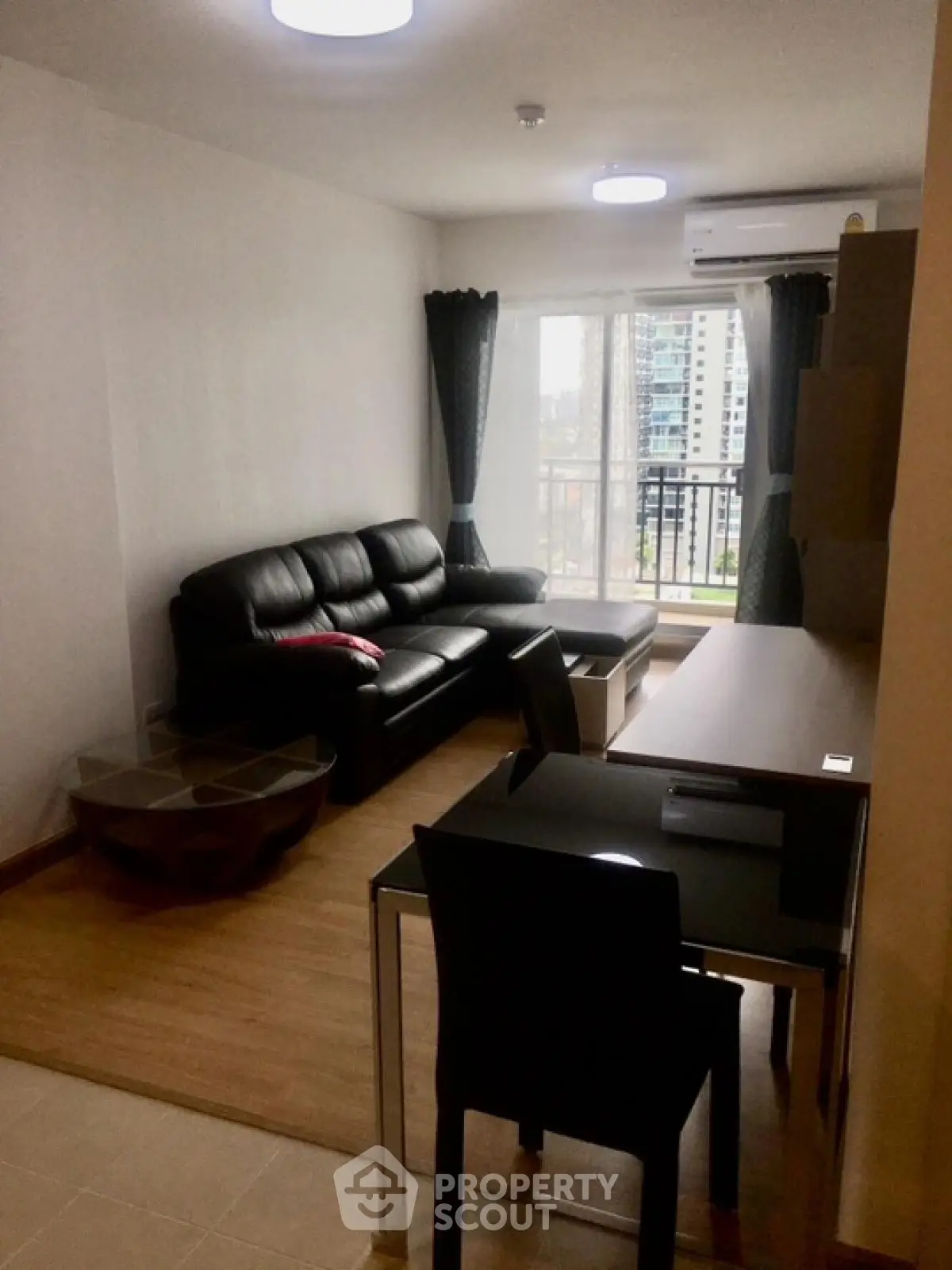 Modern living room with black leather sofa and city view balcony