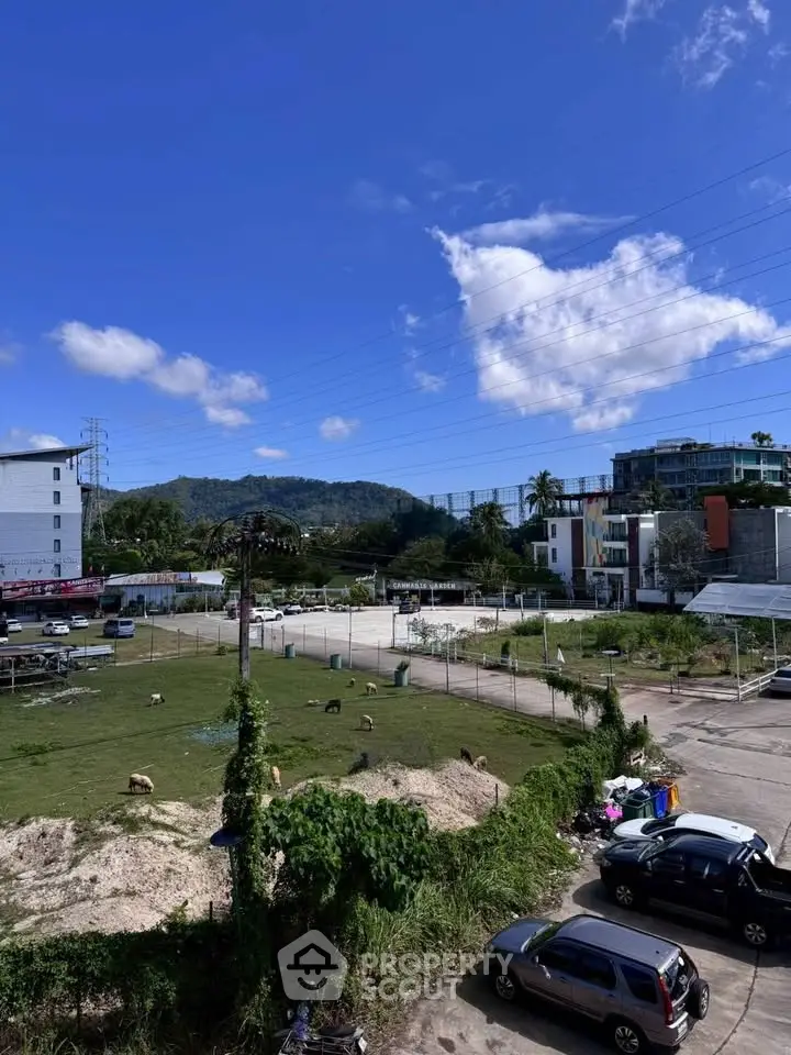 Scenic view of a mixed-use development area with lush greenery and parked cars under a clear blue sky.