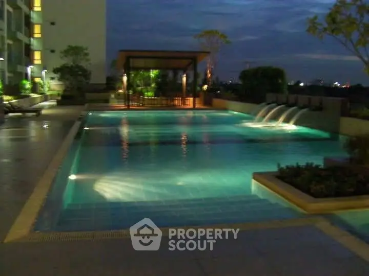 Luxurious outdoor pool with night lighting in modern residential complex.